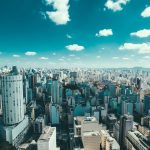 Vista aérea de São Paulo com arranha-céus e área urbana sob céu azul.