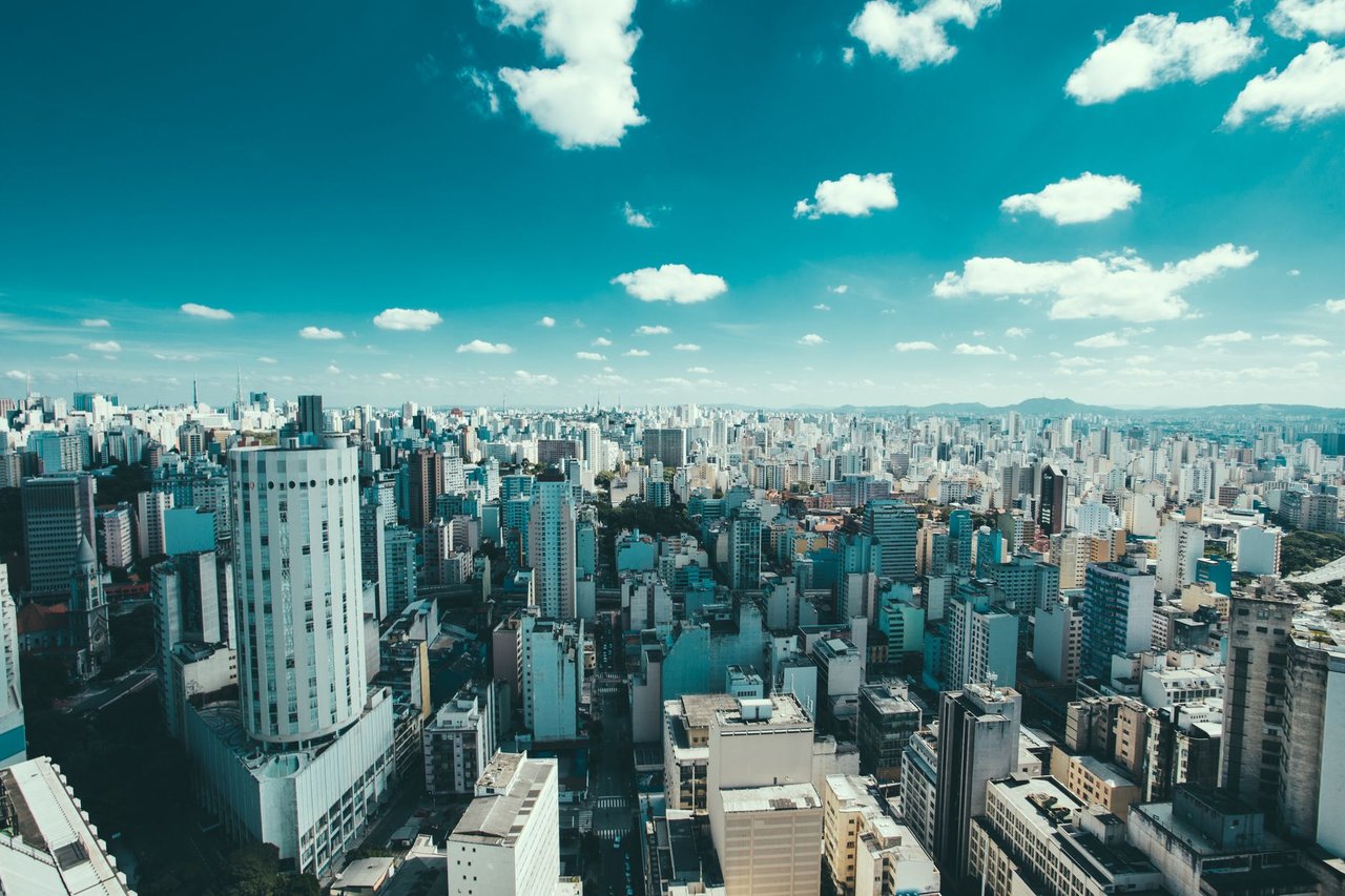 Vista aérea de São Paulo com arranha-céus e área urbana sob céu azul.