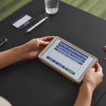 Pessoa usa um tablet para realizar o cadastro eleitoral em uma estação de votação.