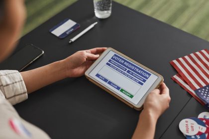 Pessoa usa um tablet para realizar o cadastro eleitoral em uma estação de votação.