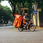 Entregador profissional transporta mercadorias em uma motocicleta por uma rua movimentada da cidade.