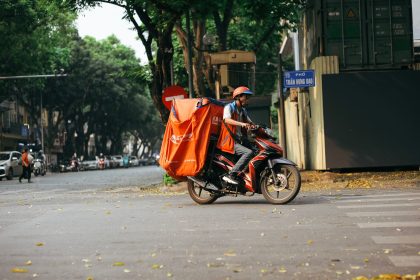 Entregador profissional transporta mercadorias em uma motocicleta por uma rua movimentada da cidade.